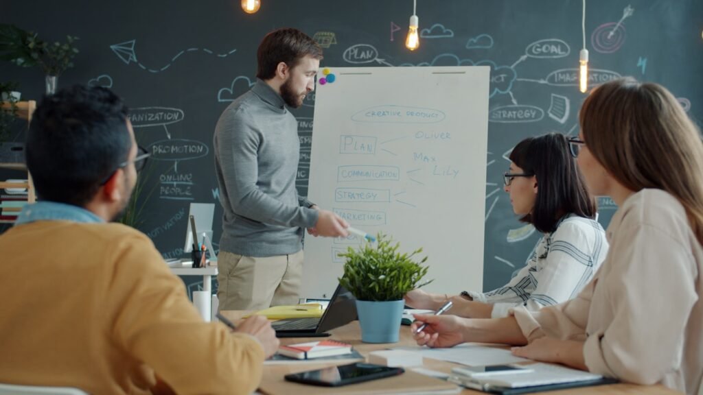 Kiwee Media team collaborating around a whiteboard discussing marketing strategy